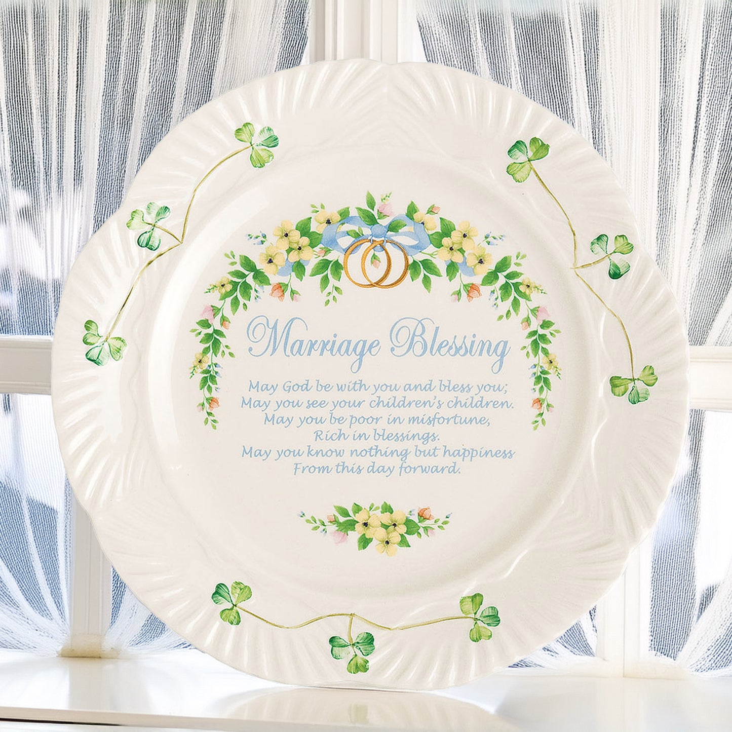 belleek marriage blessing plate
a decorative plate with floral design, featuring shamrocks, rings, and 'marriage blessing' text on a white background displayed on sideboard in with a window behind.