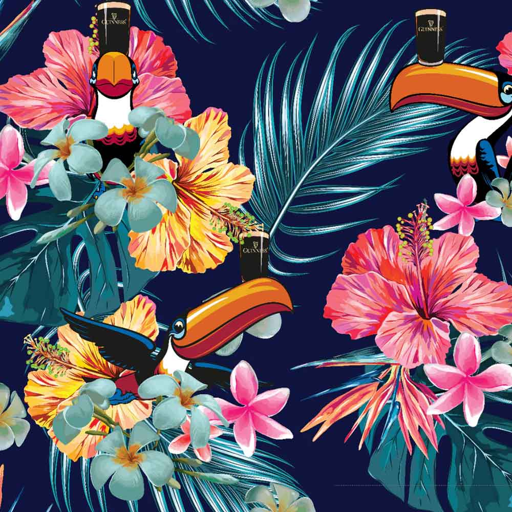 closeup view of the graphic on the guinness® toucan hawaiian shirt with colorful florals and toucans balancing glasses of guinness® on their beaks on a navy background.