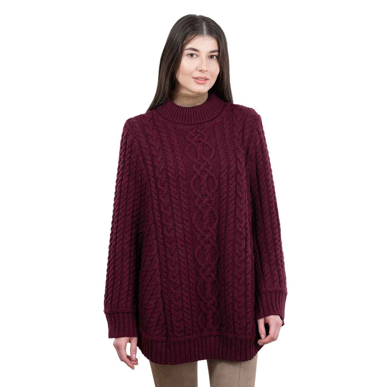 woman wearing a wine colored aran cable knit ponchor on a white background