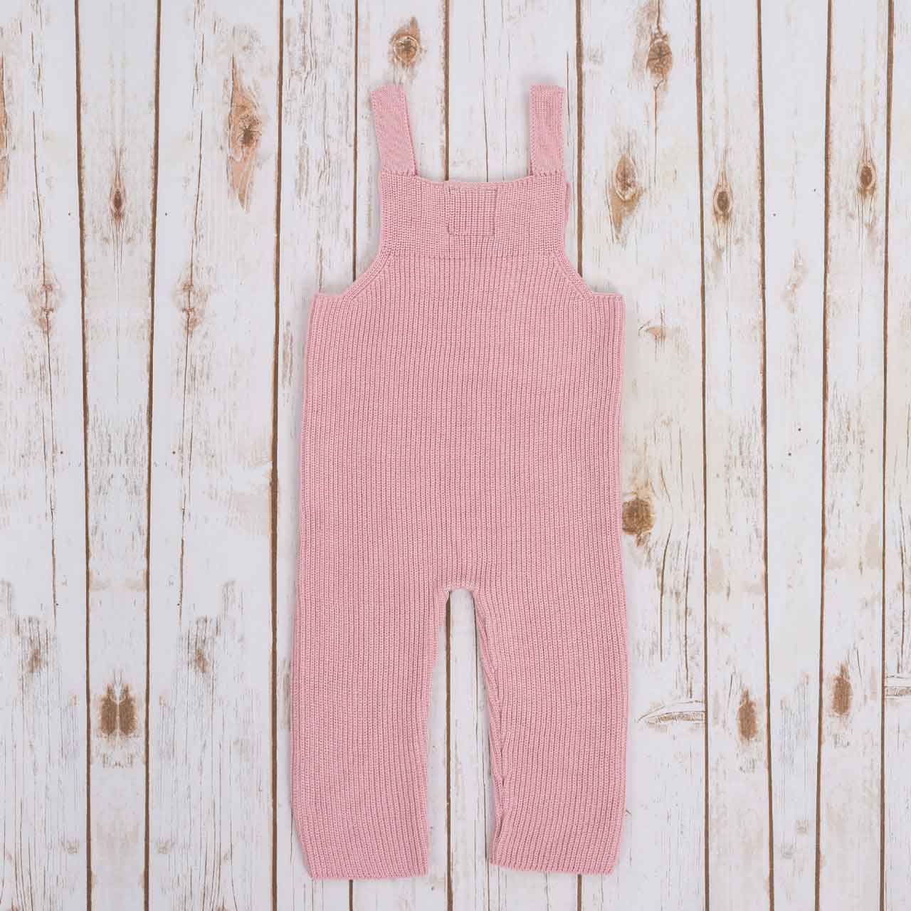 reverse view of pink irish baby knitted romper, on a wooden background
