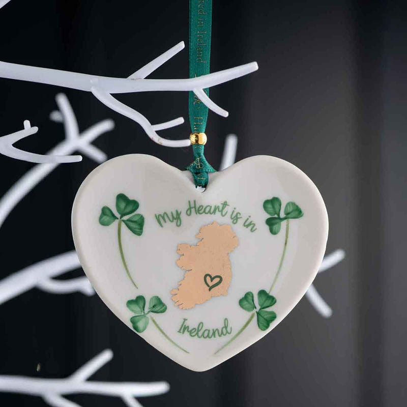 Belleek Heart-shaped ornament with 'My Heart is in Ireland' text and shamrocks hanging on a Christmas Tree against a dark background.