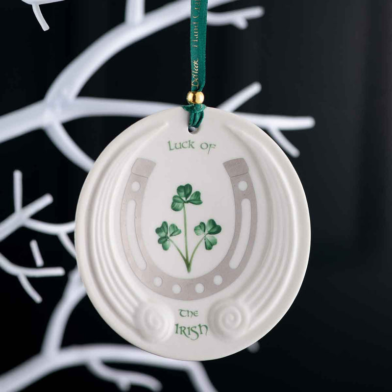 Belleek Luck Of The Irish Ornament - An oval decorative ornament with shamrock design, horseshoe and  and text reading Luck of the Irish hanging on a Christmas tree