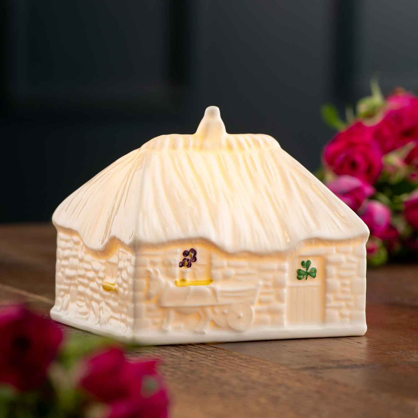 2025 led irish thatched cottage a cottage-shaped night light with shamrock design, with details like a donkey and cart on a wooden surface with flowers.