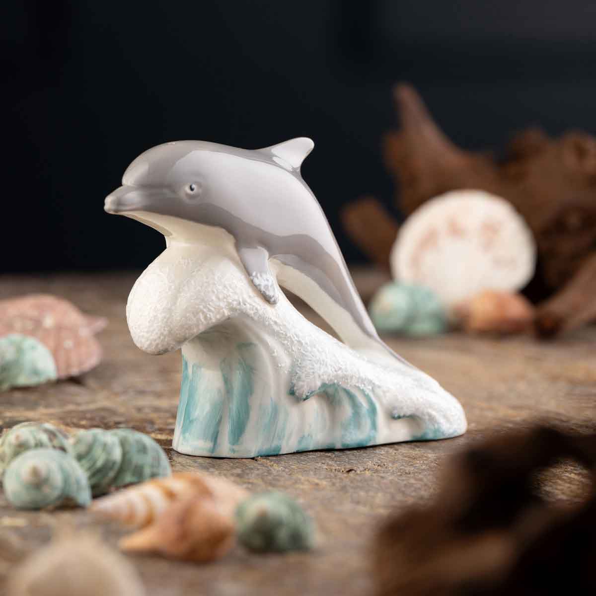 belleek pottery dolphin on a wave figurine against a blurred background surrounded by seashells