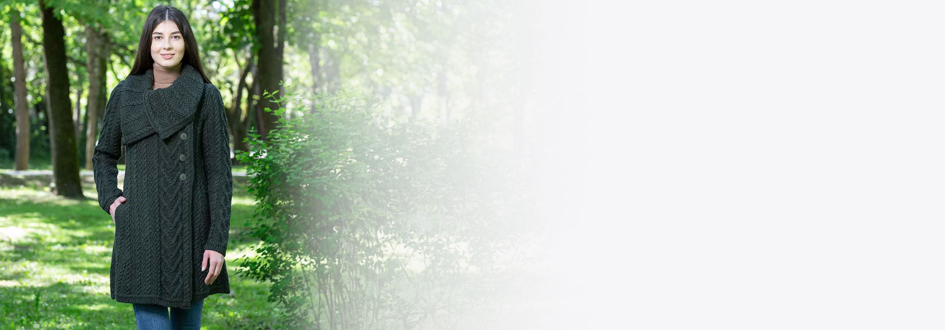 Woman modelling a dark green aran knit coat in a forest