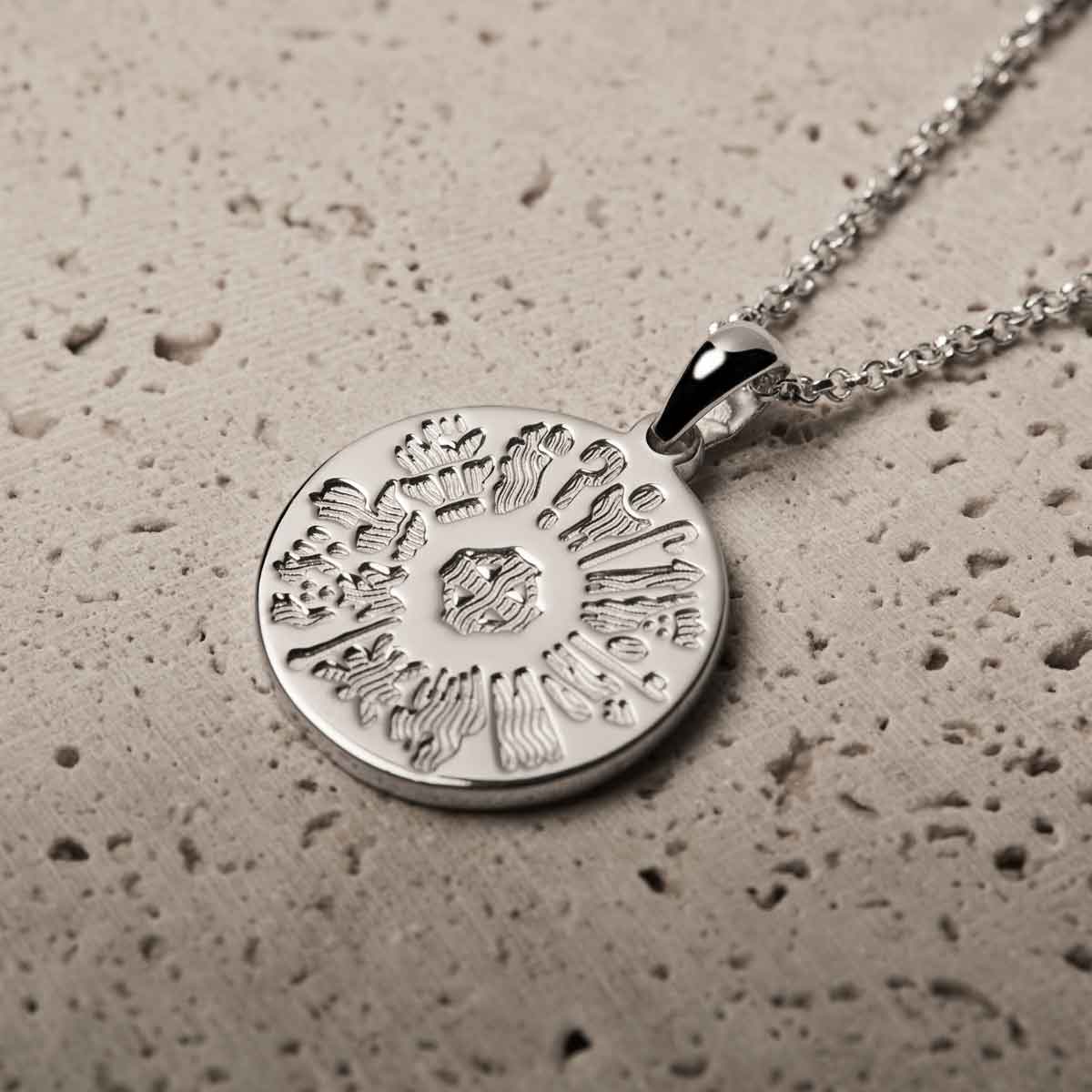 history of ireland sterling silver disc irish pendant on a textured beige surface