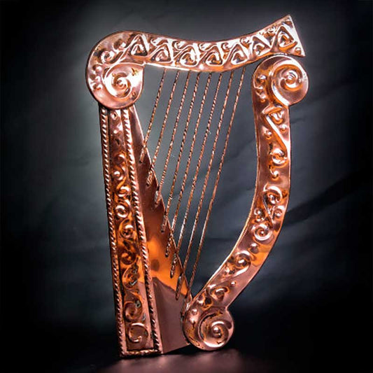Decorative copper harp plaque with embossed Celtic detail against a dark background