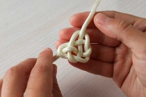 Hands tying a Celtic Knot