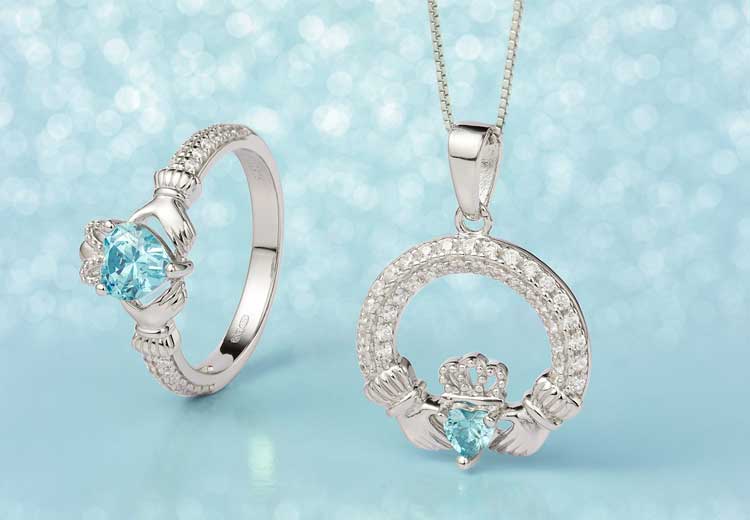 Sterling Silver Crystal Birthstone Claddagh Ring and Necklace with March's Gemstone Aquamarine against a light blue backdrop