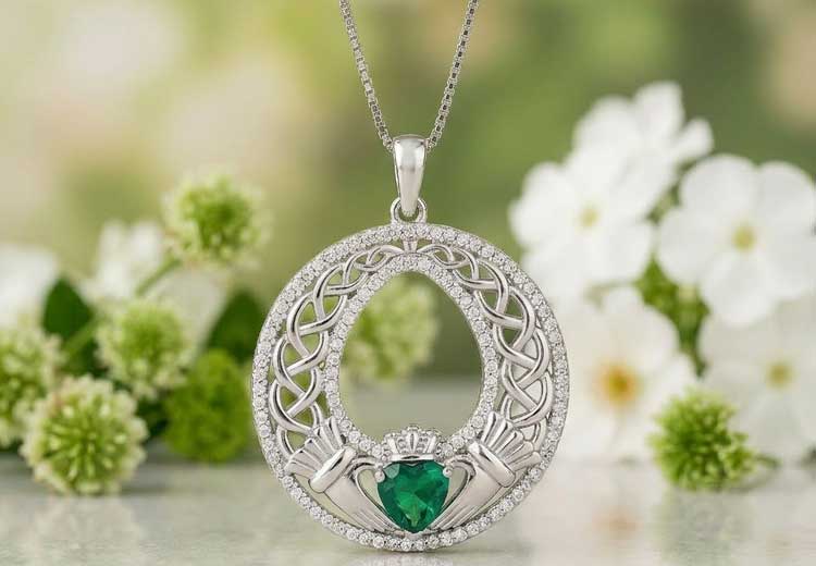 Sterling Silver Celtic Claddagh Necklace with Green Crystal in front of a floral backdrop