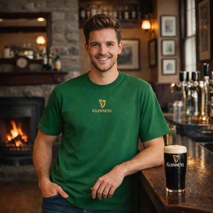 Man wearing a Guinness® Are you Toucan to Me Green T-shirt in a bar setting with a pint of Guinness on the counter.