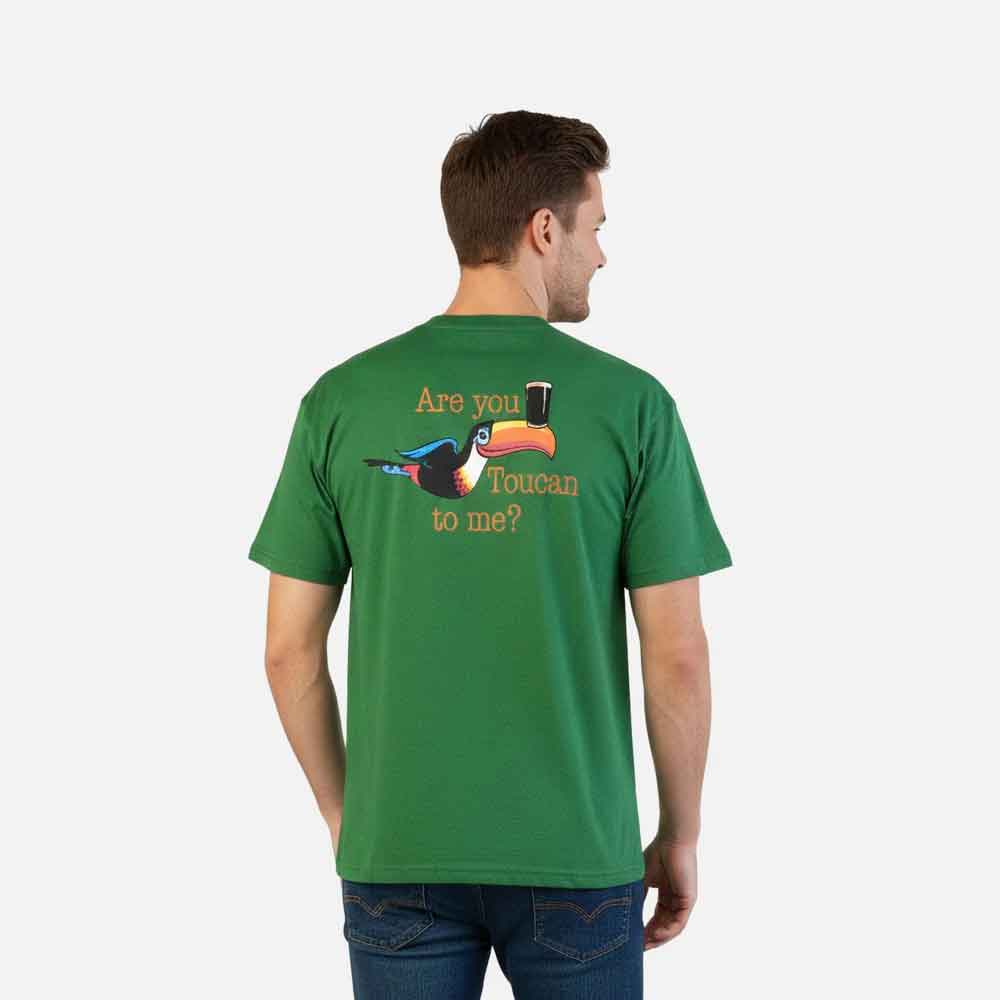 man wearing a guinness® are you toucan to me green t-shirt with a toucan graphic and are you toucan to me? text on the back, on a white background