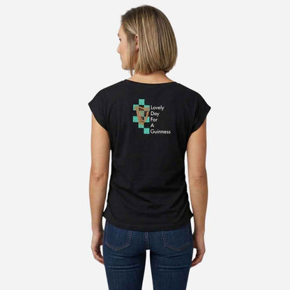 Woman wearing a Guinness® Hawaiian Ruched Ladies Black t-shirt with 'Lovely Day for Guinness' text and harp logo on the back.