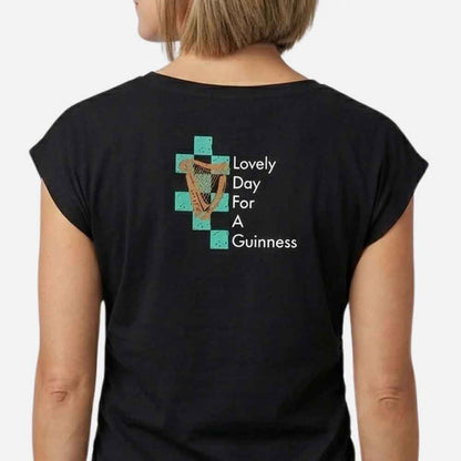 Woman wearing a Guinness® Hawaiian Ruched Ladies Black t-shirt with closeup of the graphic design reading 'Lovely Day for Guinness' text and harp logo