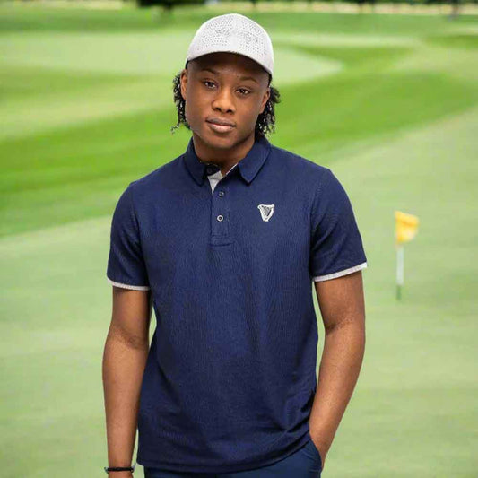 Person wearing a Guinness® Navy Performance Polo Shirt on a golf course