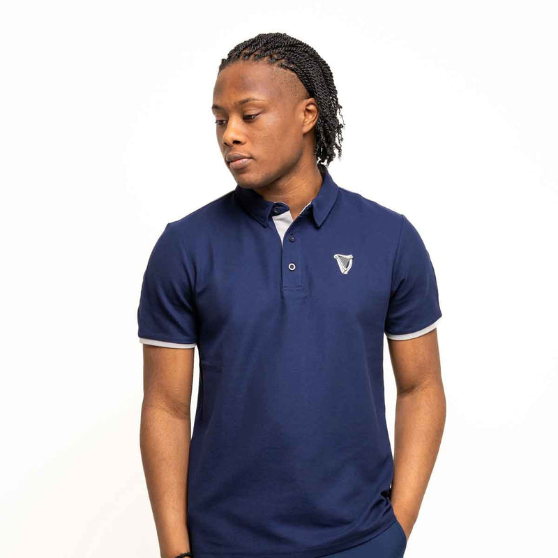 Person wearing a Guinness® Navy Performance Polo Shirt on a white background