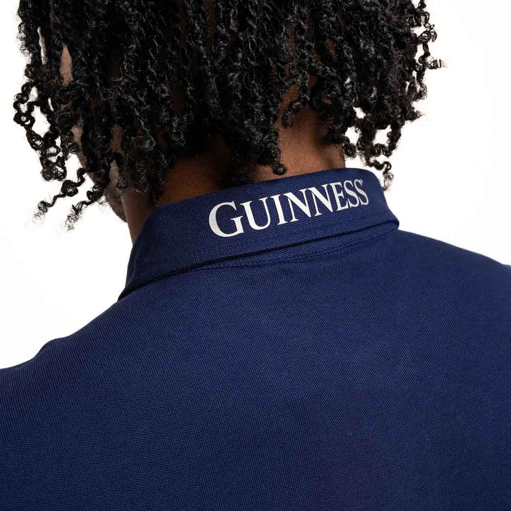close up of guinness® navy performance polo shirt with 'guinness' embroidered logo on the collar.