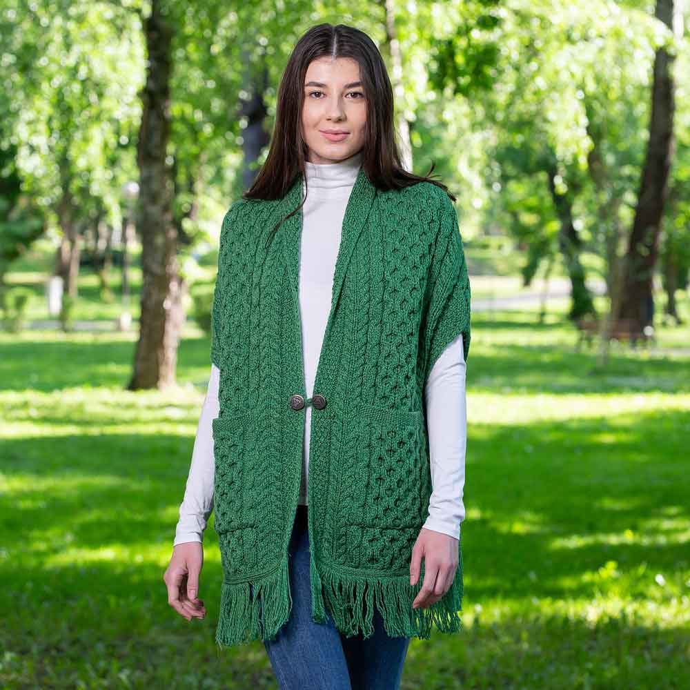 woman wearing a green aran knit ladies pocket shawl in a park.