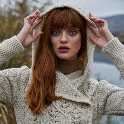 A close-up view of a woman raising the hood of her  parsnip-colored Ladies Aran Leaf Cable Knit Coat