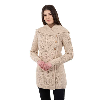 Woman wearing a parsnip-colored Ladies Aran Leaf Cable Knit Coat in front of white background