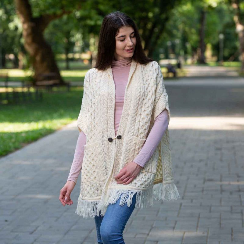 Woman wearing a white/natural Aran Knit Ladies Pocket Shawl in a park setting