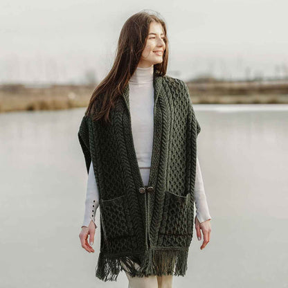 Woman wearing an Army green Aran Knit Ladies Pocket Shawl standing in front of lake