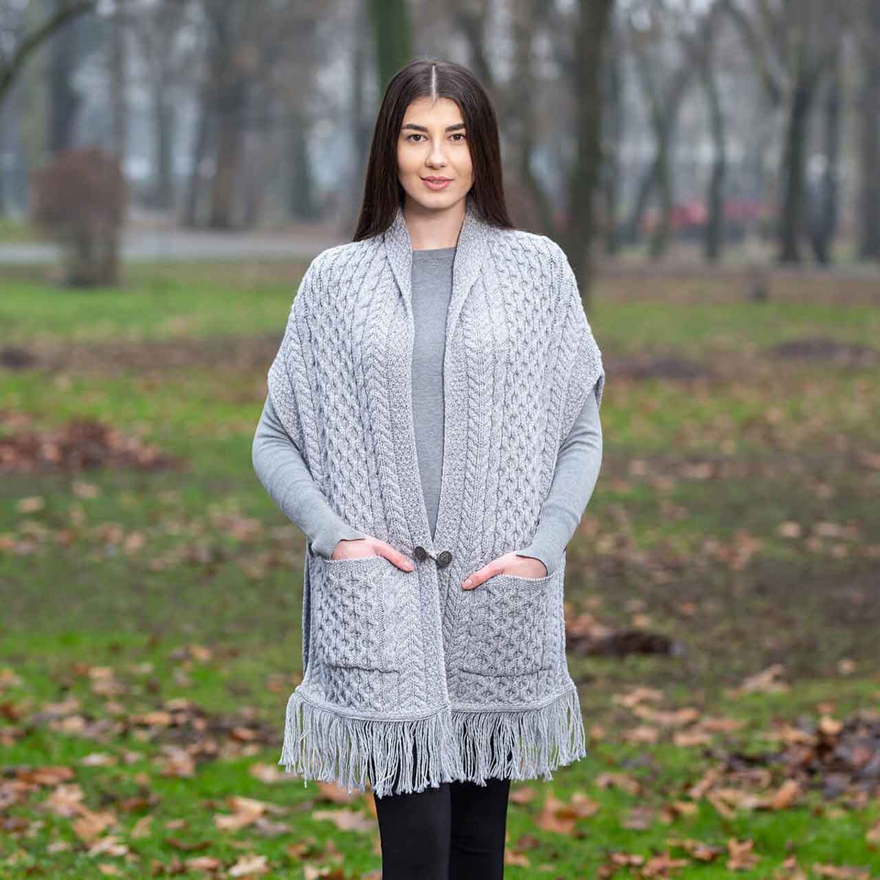 woman wearing a gray aran knit ladies pocket shawl in a park setting