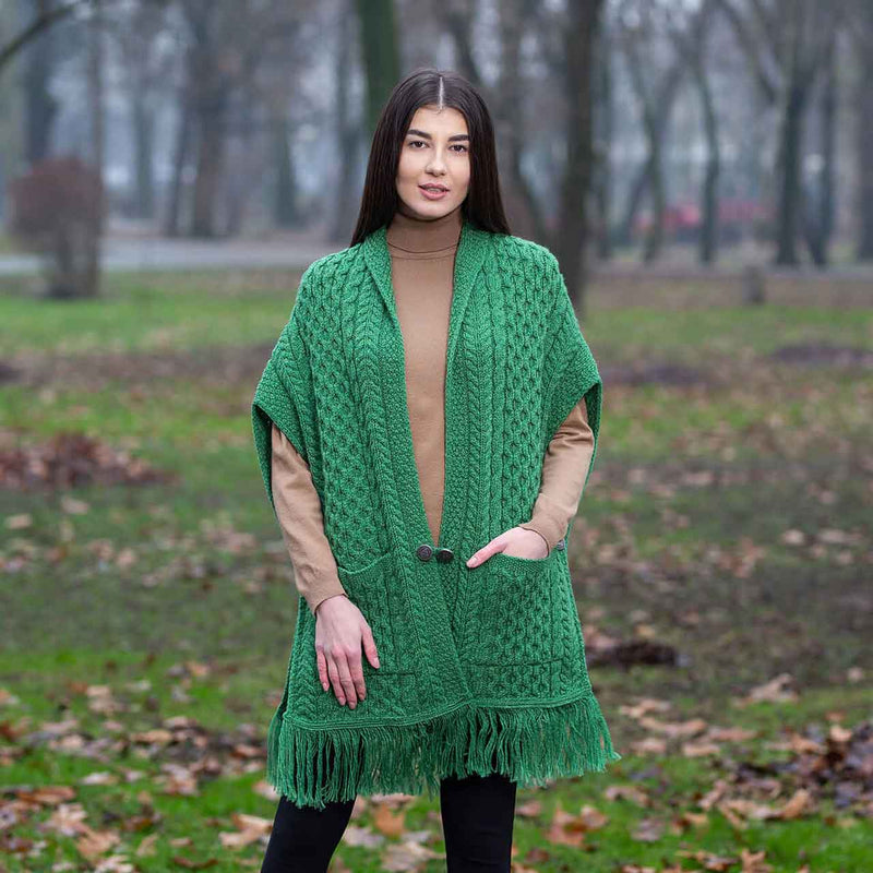 Woman wearing a green Aran Knit Ladies Pocket Shawl in a park setting