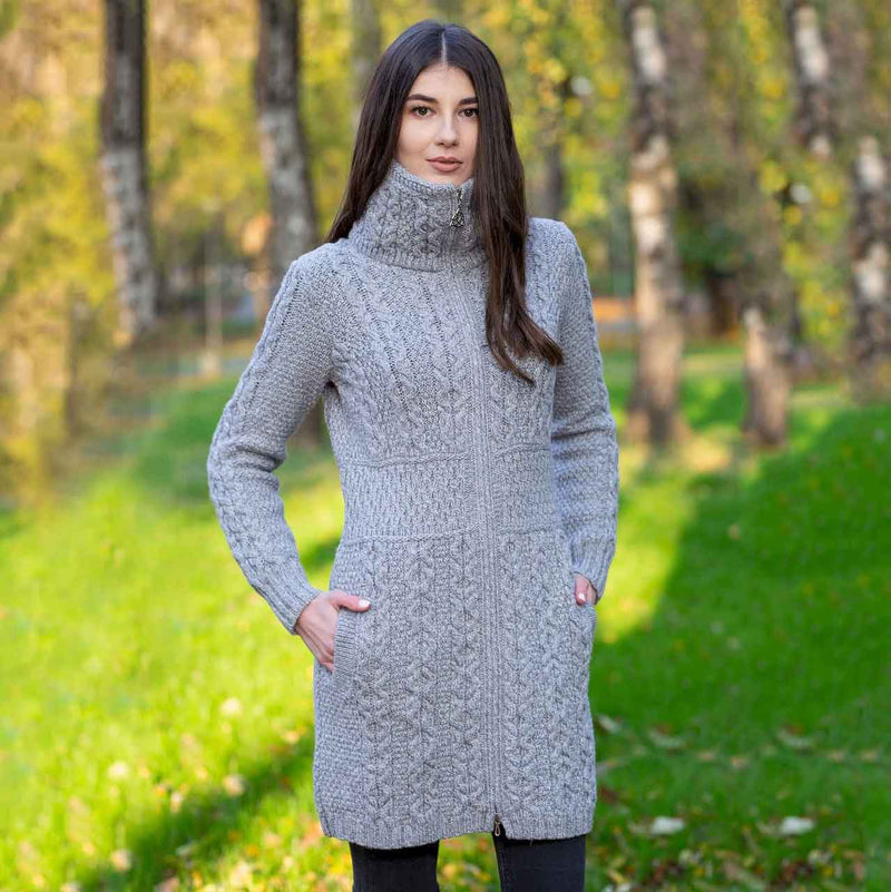 Woman wearing a grey Irish Aran double collar zip ladies cardigan knitted coat standing in a forest