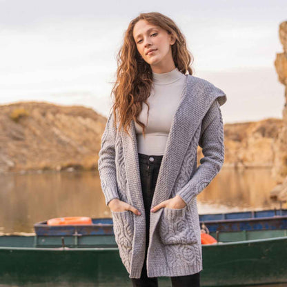 Woman wearing a gray Aran Knit Hooded Ladies Long Cardigan by a lake with mountains in the background