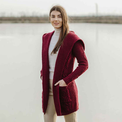 Woman wearing a wine Aran Knit Hooded Ladies Long Cardigan in front of a lake 