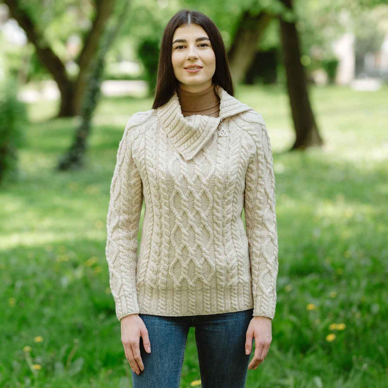 Woman wearing a parsnip-colored Irish Aran ladies merino wool zipper neck sweater in a park setting