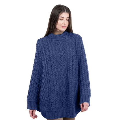 Woman wearing an Ocean Blue Aran Cable Knit Poncho cable knit sweater on a white background