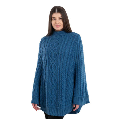 Woman wearing a teal Aran Cable Knit Poncho on a white background