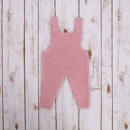 Pink Irish baby knitted romper overalls on a wooden background