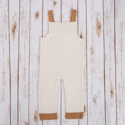 Reverse view of White Irish baby knitted romper with  brown cuffs, on a wooden background
