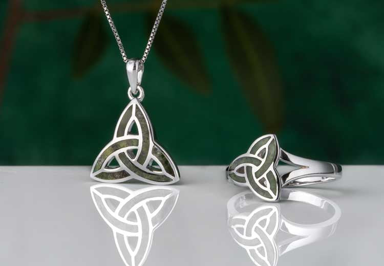 Silver Celtic Trinity Knot Necklace and Ring set with Connemara Marble on a reflective surface with a blurred green background