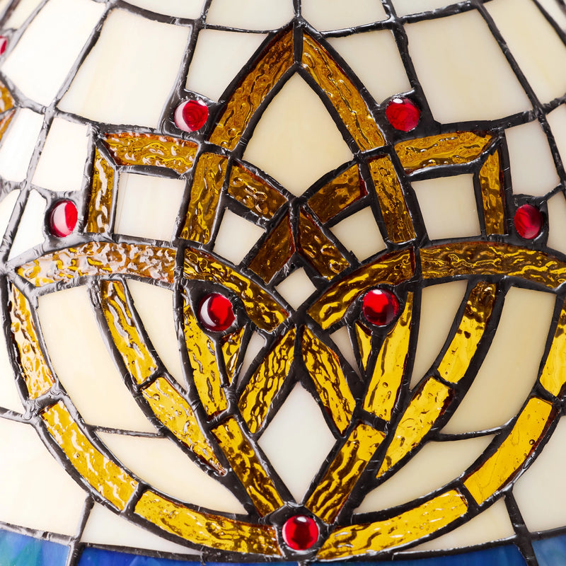 Close-up of a Celtic Blooming Flower Stained Glass Table Lamp featuring a central interlaced geometric motif in gold and amber tones, bordered by cream glass sections and accented with small red glass gems.