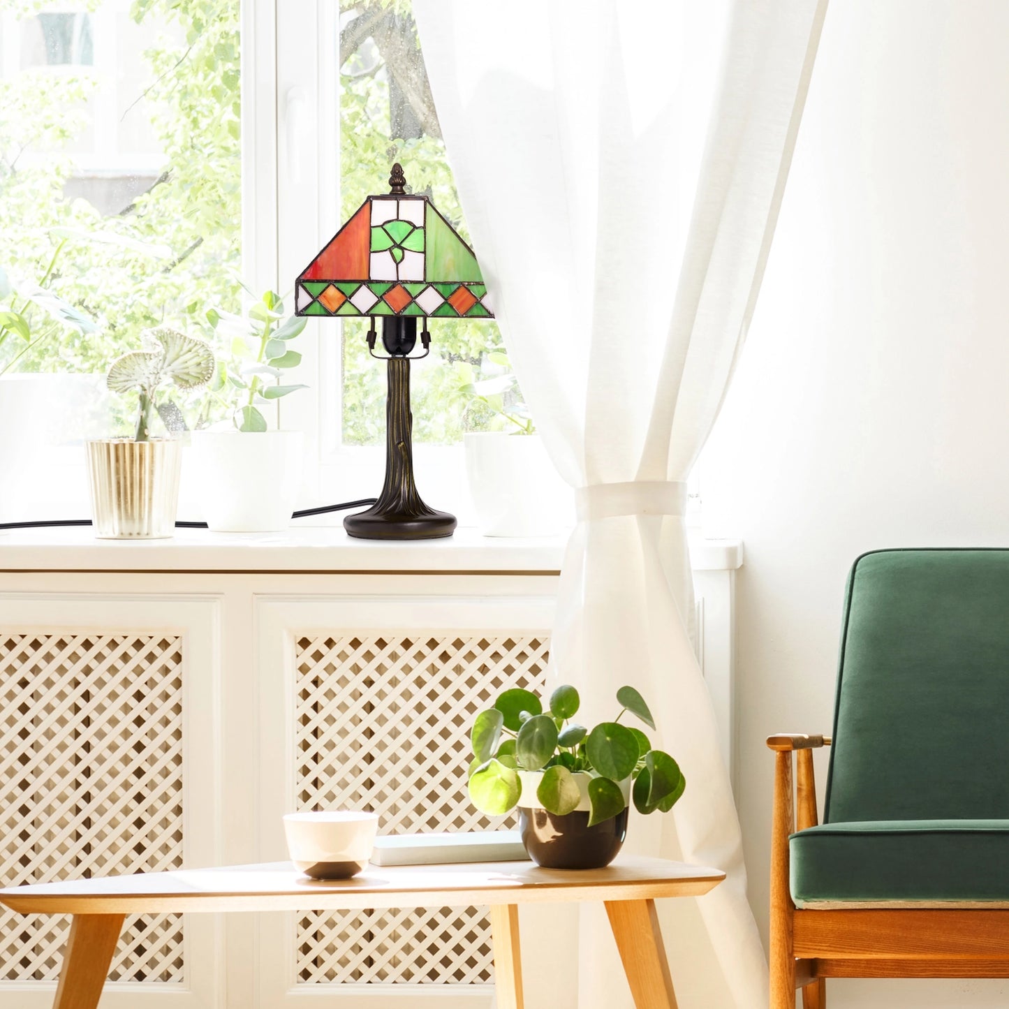 a st. patrick's day irish flag tricolor stained glass table lamp sits on a windowsill in a bright room with white curtains, a small wooden table with a potted plant, and a green armchair.