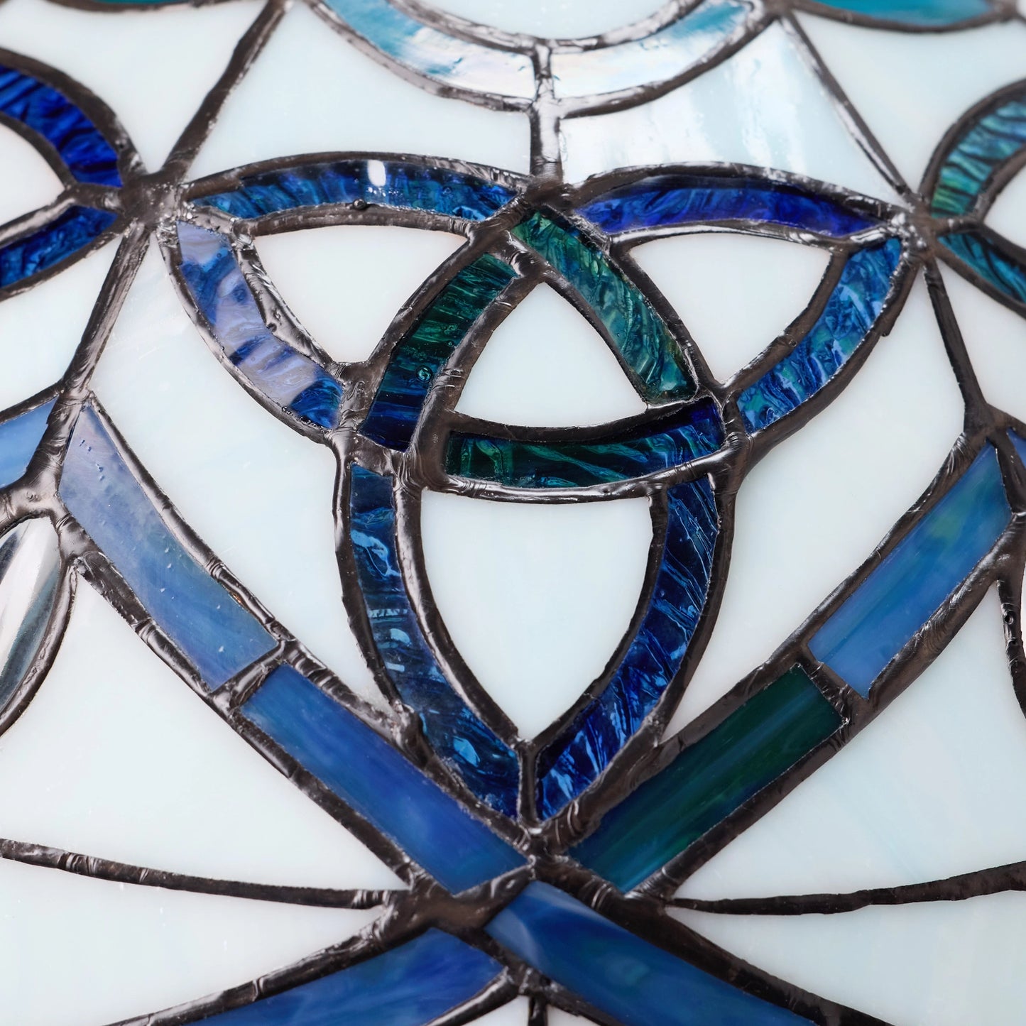 close-up of celtic stained glass dome trinity knot table lamp
with blue and green colored glass panels.