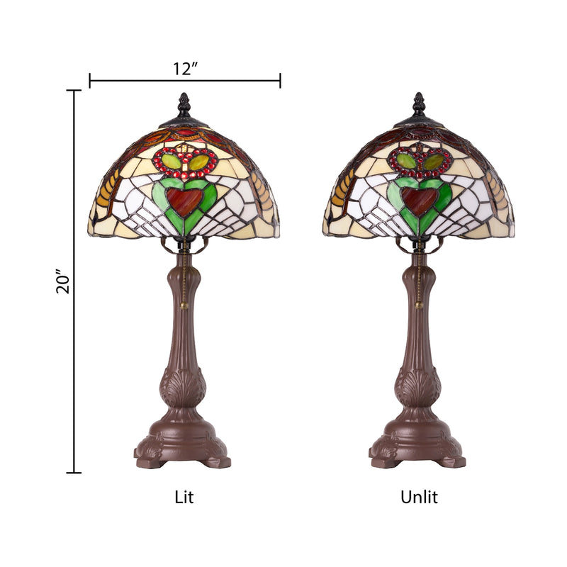 Two views of a Claddagh Stained Glass Table Lamp a white background, labeled 'Lit' and 'Unlit' with dimension lines showing 20" height and 12" width. The lamp has a bronze-toned pedestal base and a dome-shaped stained glass shade featuring a Claddagh design.