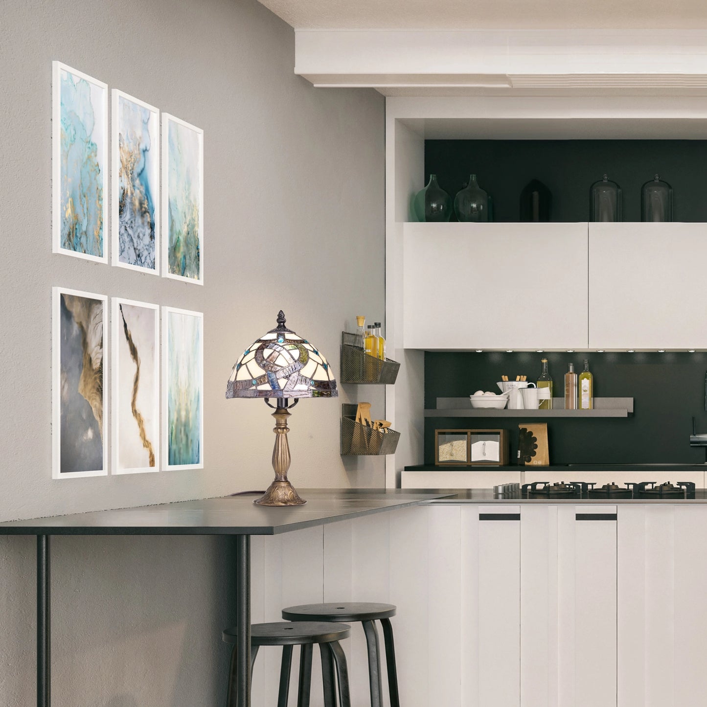 a modern kitchen interior with a bar-height counter, black stools, wall-mounted framed abstract art, celtic stained glass amber pathway table lamp on the counter.