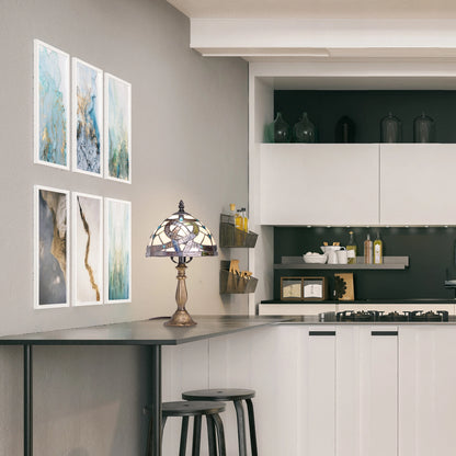 A modern kitchen interior with a bar-height counter, black stools, wall-mounted framed abstract art, Celtic Stained Glass Amber Pathway Table Lamp on the counter.