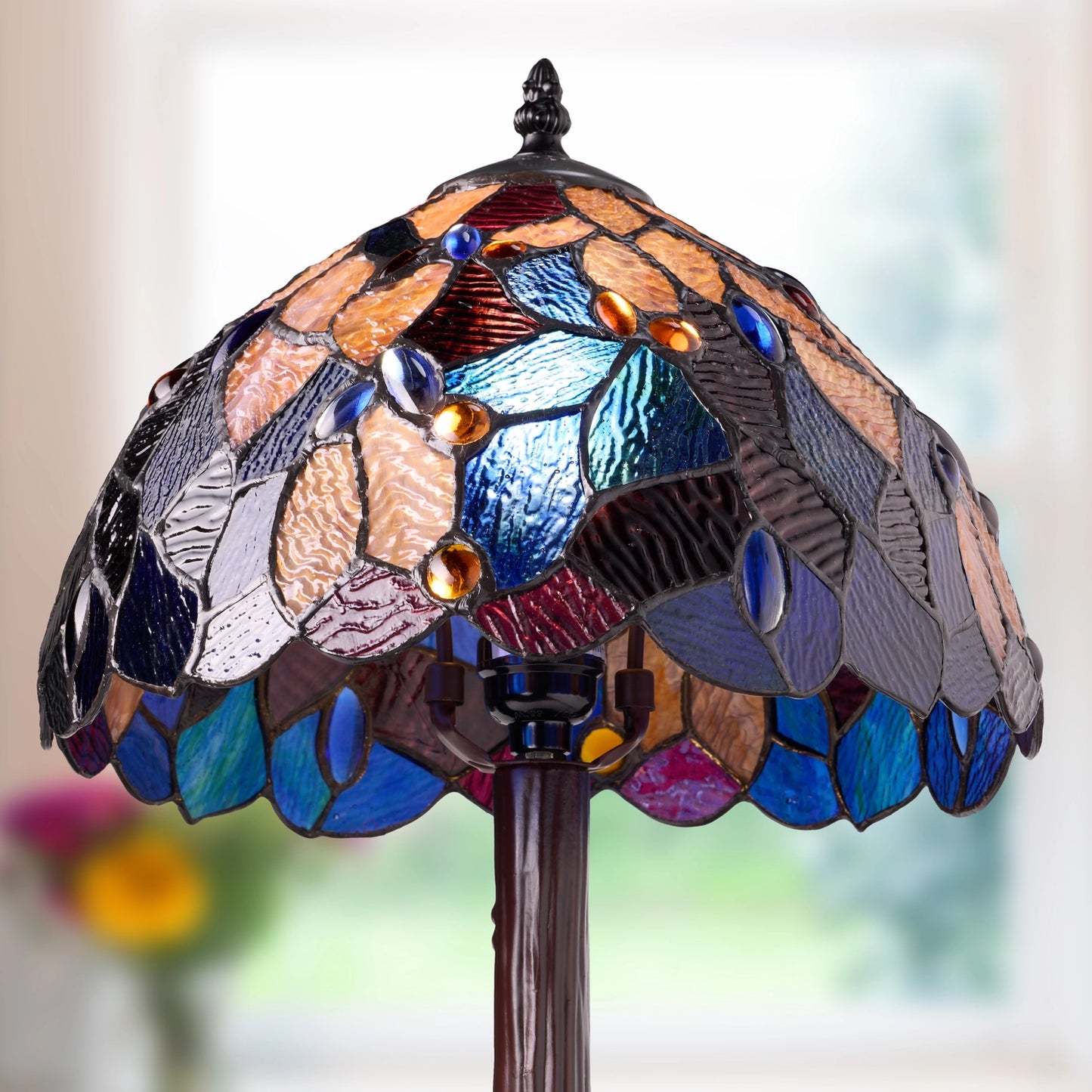celtic stained glass fairy pool table lamp with a domed, leaf-like pattern of blue, purple, brown, and amber glass panels, mounted on a dark brown resin stand against a softly blurred bright background.