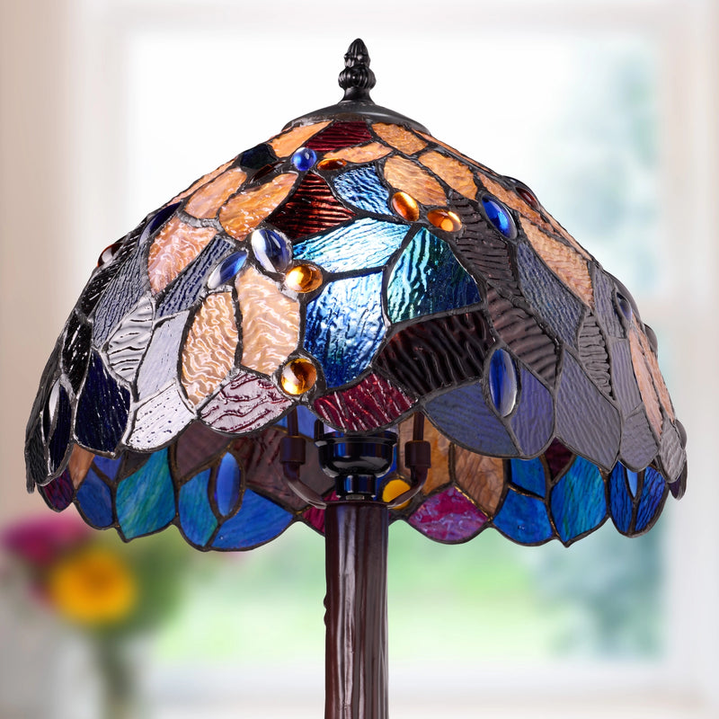 Celtic Stained Glass Fairy Pool Table Lamp with a domed, leaf-like pattern of blue, purple, brown, and amber glass panels, mounted on a dark brown resin stand against a softly blurred bright background.