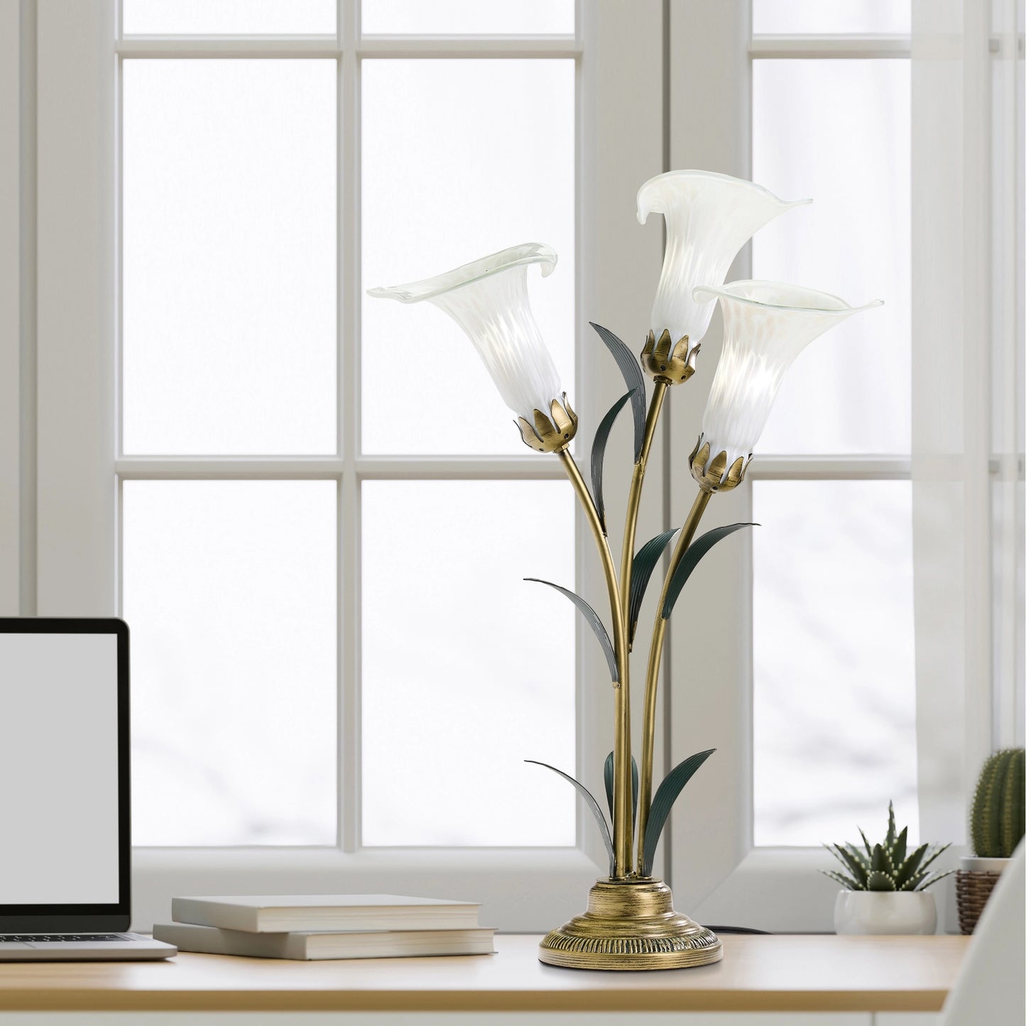 handblown glass 3 light white lily table lamp on a desk in a bright room.