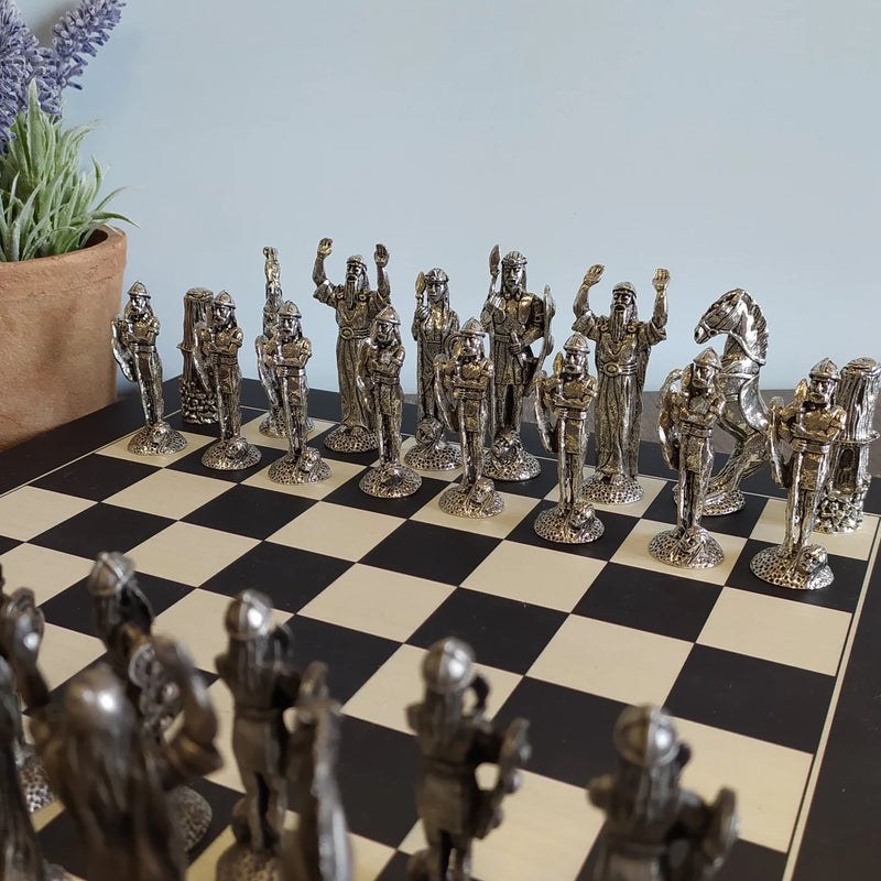 Irish Pewter Celtic Chess Set & Wooden Board with a plant in the background.
