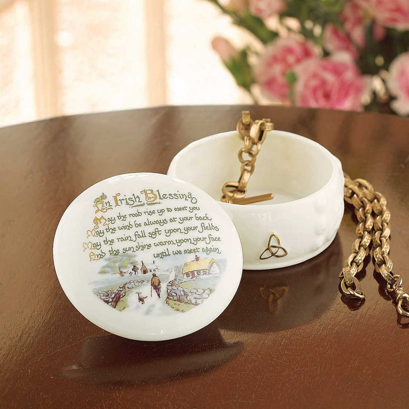 Belleek Irish Blessing Gift Box, with open lid featuring an Irish blessing text, on a wooden surface with flowers in the background