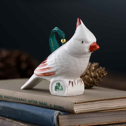 White Belleek Cardinal Irish Ornament with red accents, green ribbon and shamrock on a stack of books