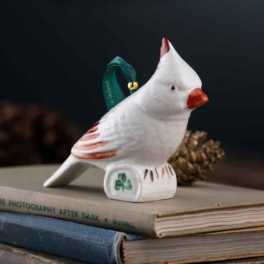 White Belleek Cardinal Irish Ornament with red accents, green ribbon and shamrock on a stack of books